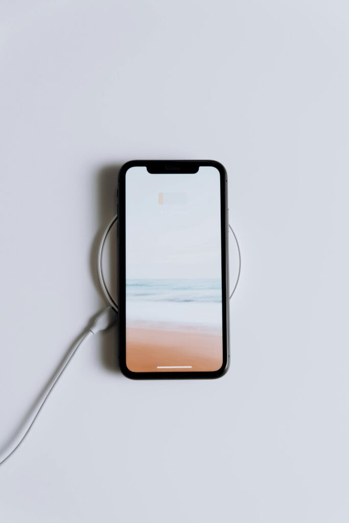 pexels-photo-5083491-5083491 Minimalist smartphone on a wireless charger with a serene beach wallpaper.